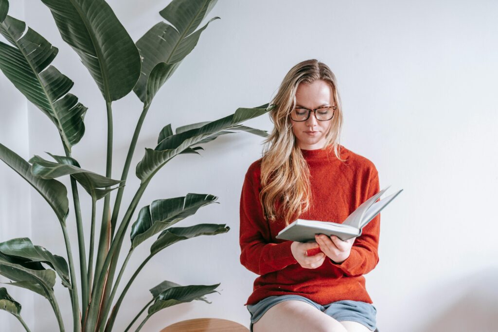 Woman wearing a rust orange sweater reading a book
