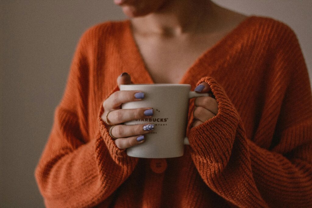 Woman wearing loose, cozy cardigan holding a cup of coffee