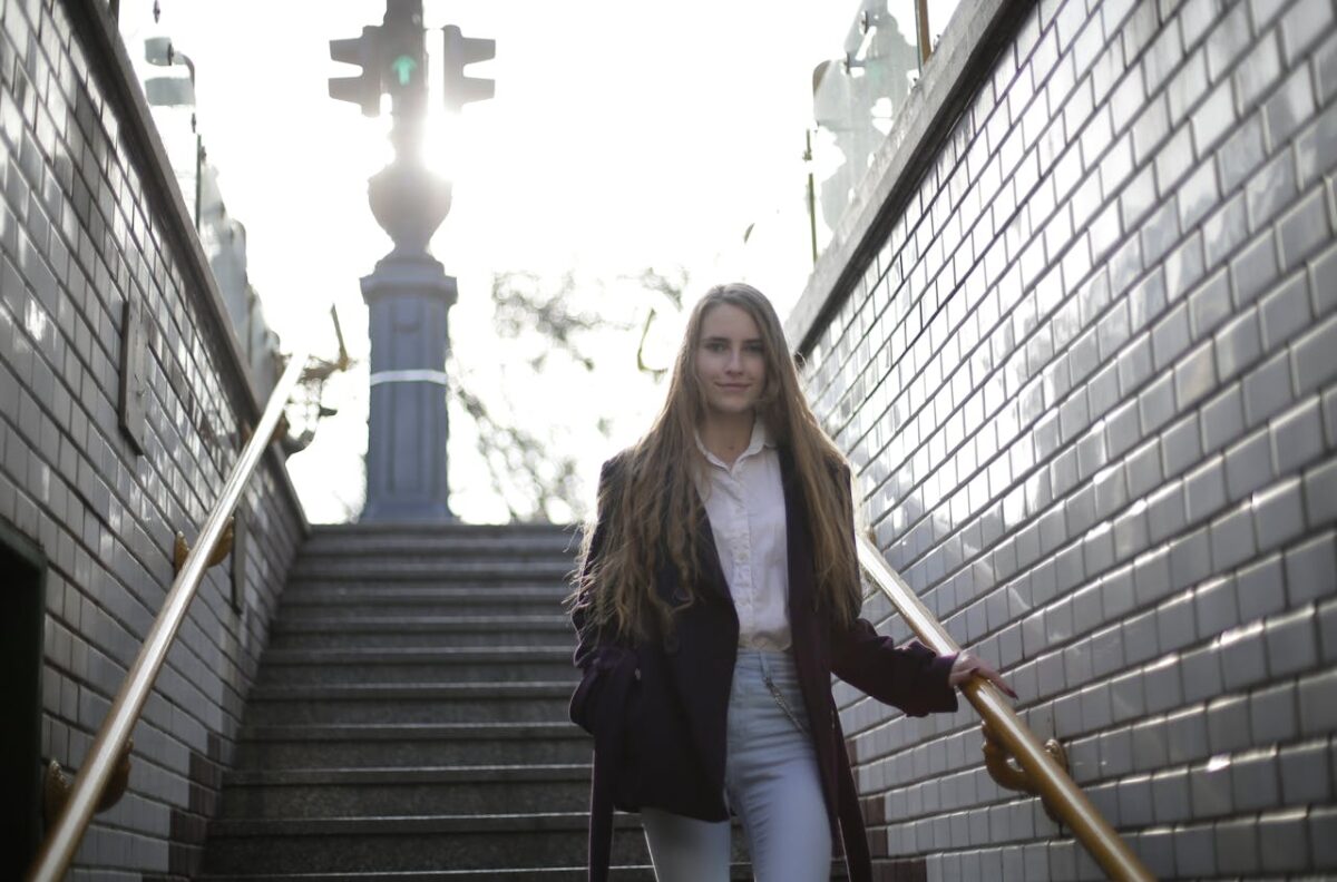 Woman walking down subway stairs in a casulal blazer, button down shirt, and jeans