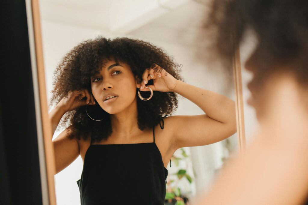 Woman looking in the mirror trying to decide what earrings to wear