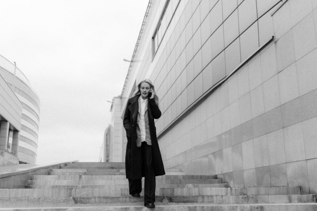 woman in wide leg trousers walking down stairs and talking on a phone
